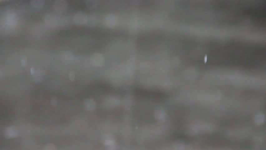 Closeup raindrops drip floor on blurr background. Rain water falls down on gray floor as bokeh background. Rain drops crash outdoor floor on heavy rain. Rainy day footage for rainy weather background.