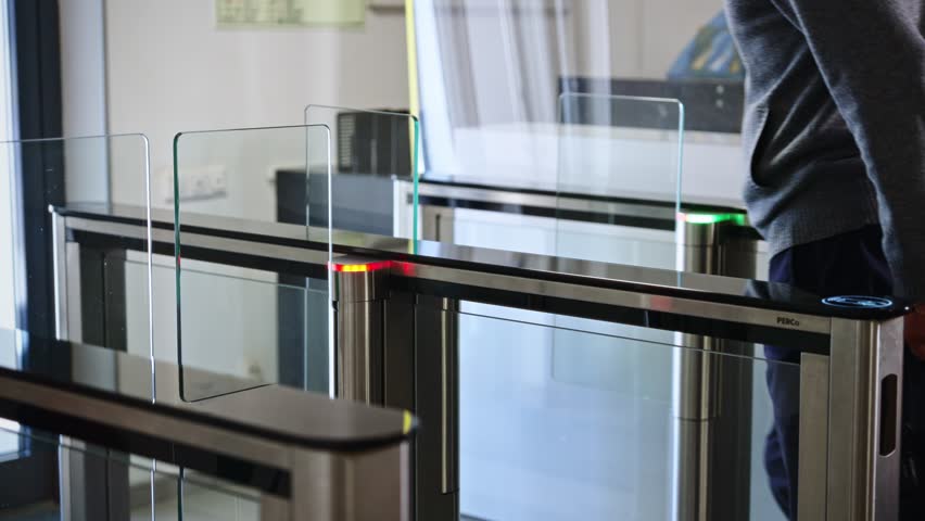 Passing through a turnstile into an office building. Office workers enter and exit through a modern turnstile, using a key card to enter.