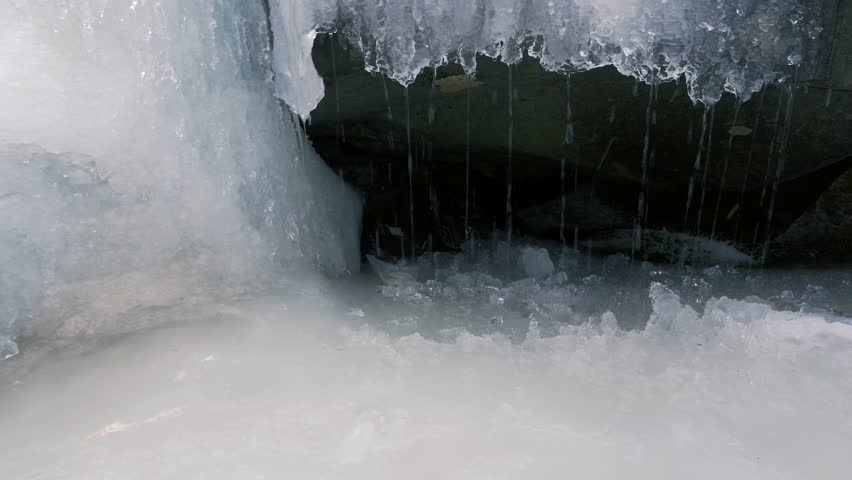 An Icy Waterfall Coming Out Of A Cave In The Woods.