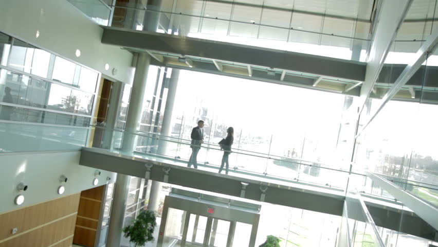 Backlit businessman and woman meet against a backdrop of white windows. Low