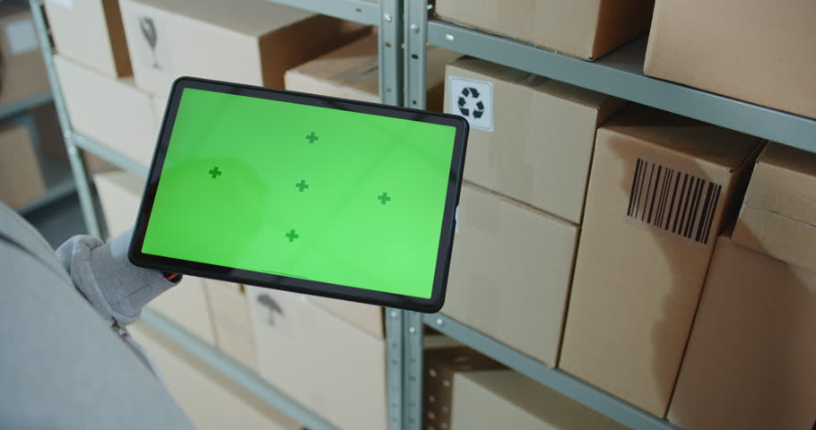 Postal Warehouse Associate Scans Code on Cardboard Box with Barcode Scanner, Checks Parcel Information, Tracks Package Delivery Route. Tablet Computer Screen Shows Green Screen Chroma Key. Close Up.