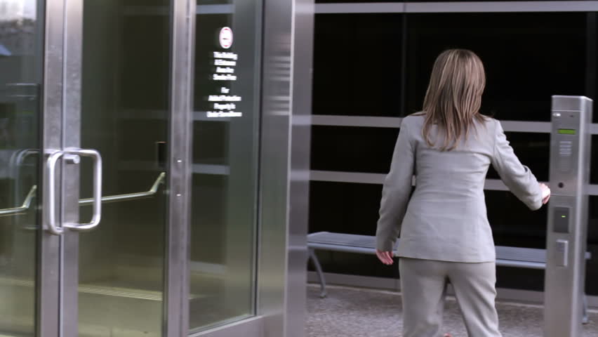 Businesswoman tries repeatedly to use her security pass to enter a modern office