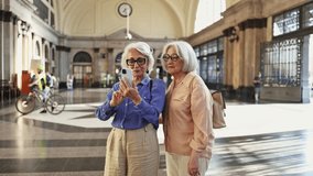 Senior tourists taking selfies in train station. Senior women friends taking selfies with smartphone, capturing joyful moments during train station travel adventure - Powered by Shutterstock - Get 15% off with code: PIKWIZARD15