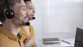 Focused male call center operator in yellow casual shirt is assisting clients online, providing customer support and answering inquiries. Call center operators - Powered by Shutterstock - Get 15% off with code: PIKWIZARD15