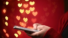 Female hands are holding phone and texting messages on red background with hearts bokeh. Online communication. Greeting of a Valentine's Day, wedding, anniversary, engagement. - Powered by Shutterstock - Get 15% off with code: PIKWIZARD15