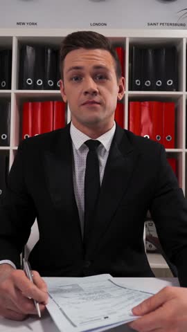 4k POV. Ultra HD. Handsome young salesman business person entrepreneur inviting you to sign a lease or a service agreement. Indoor office portrait shot. Vertical Shot.