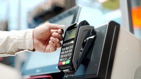 Close up man At Counter Buy electronic payment supermarket by credit card close-up. Male hand pay for purchases in stores Contactless NFC pos Terminal Closeup card reader at cashless wallet - Powered by Shutterstock - Get 15% off with code: PIKWIZARD15