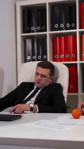 Two laziness idleness idleness bored employee playing small ball on work place table with computer desktop. I Don't want to do anything helpful or useful on my workplace concept. Vertical Shot.