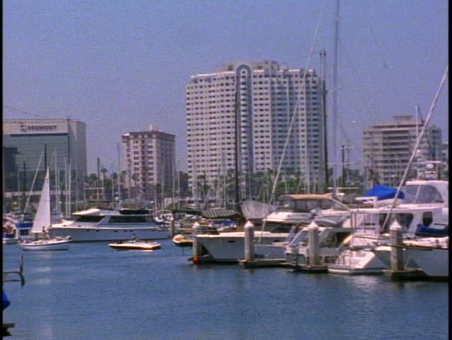 Marina del Rey Yacht Basin of Los Angeles with boats berthed, sailboat passing
