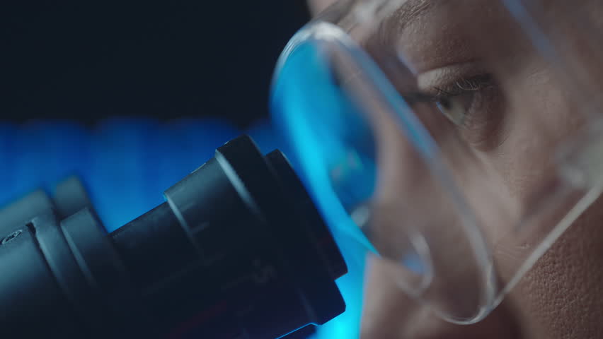 Female virologist scientist using microscope in laboratory. Biochemical and medical research. Pharmacist specialist working with lab equipment analyzing samples and searching for vaccine development