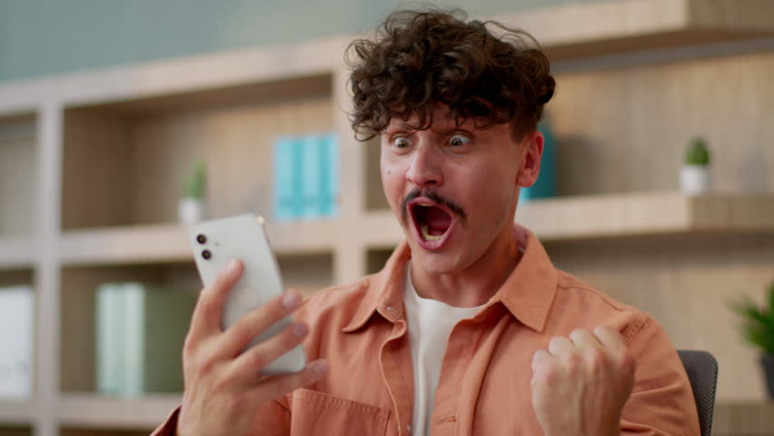 Happy winner Caucasian man cheerful business guy businessman male in office celebrate online betting victory internet gambling addict mobile phone lottery prize money winning shock success smartphone