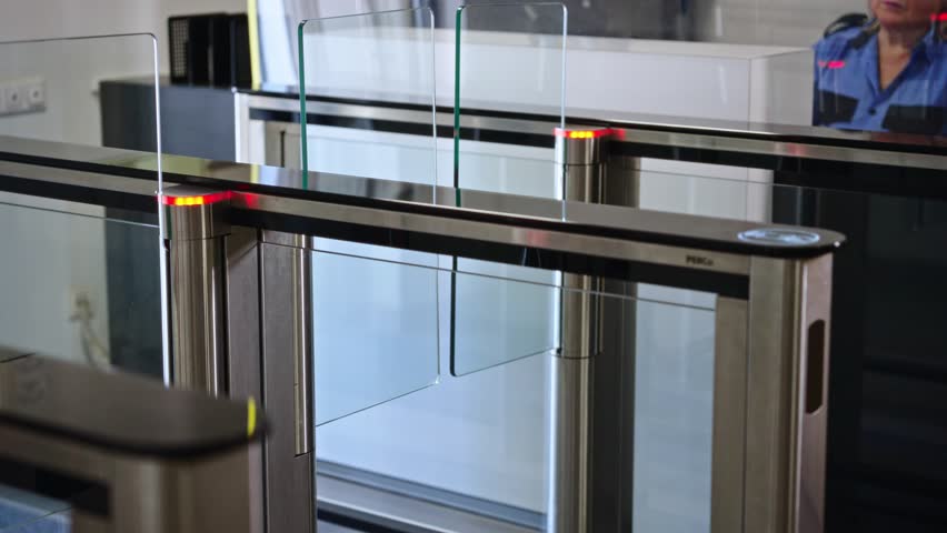 Passing through a turnstile into an office building. Office workers enter and exit through a modern turnstile, using a key card to enter.