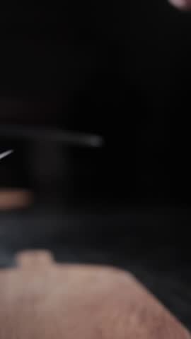 A vertical slow-motion of a chef picks his knife professionally and start to sharpen it