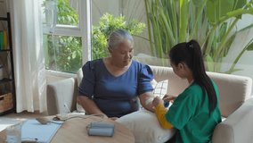 Young female medical worker putting bandage on arm of Asian senior woman while preparing her for IV drip infusion at home - Powered by Shutterstock - Get 15% off with code: PIKWIZARD15