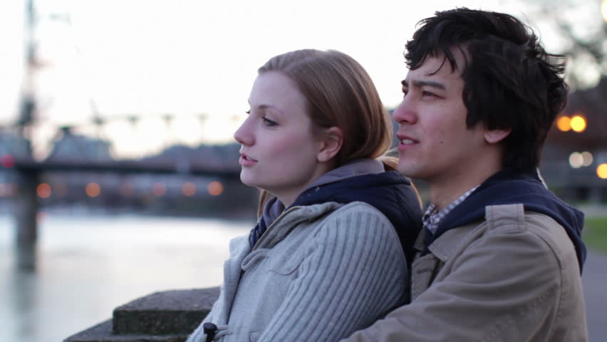 Attractive young couple hanging out, watching the Willamette River at dusk in
