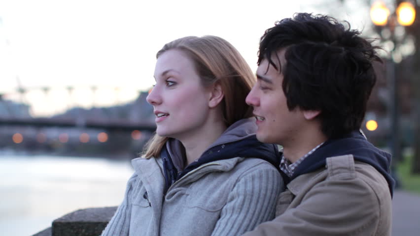 Attractive young couple hanging out by the Willamette River at dusk in Portland,