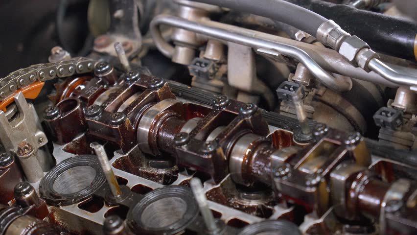 Mechanic tightening bolts on car engine's camshaft cover using socket wrench. Focus on precision and skill in automotive repair and maintenance within workshop environment