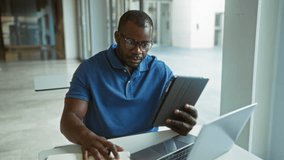 Young man working on a tablet in a bright office setting with a laptop and notebook, embodying a modern professional workplace atmosphere. - Powered by Shutterstock - Get 15% off with code: PIKWIZARD15