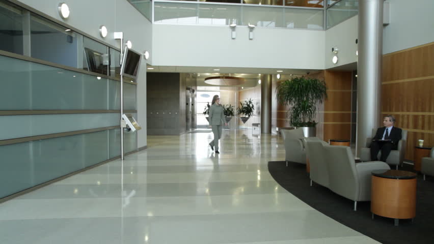 Various people passing through a modern office lobby, disolving in and out of