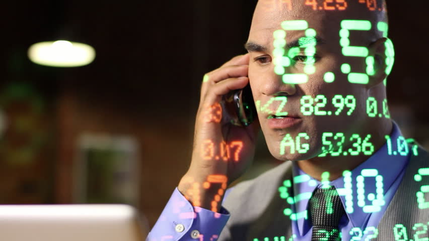 City guy making deals on the phone while ticker symbols of varying size are