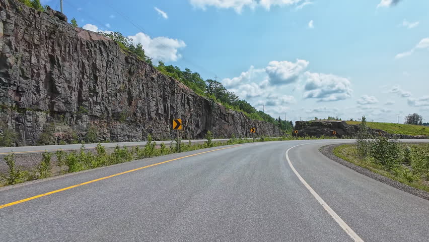Breathtaking view of a highway 11 winding road through lush forests with rocky walls layer. Scenic travelling car plate. Leftside driver's POV. Driving plate road trip along the mountains asphalt road