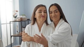 Mother and daughter embracing in a spa room wearing white robes, reflecting family love and wellness in an indoor salon setting - Powered by Shutterstock - Get 15% off with code: PIKWIZARD15