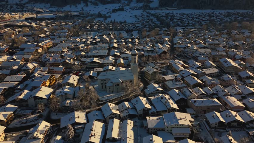 St. Martin, the Catholic parish church in Garmisch, part of Garmisch-Partenkirchen, Germany, is shown in an aerial view, nestled in a picturesque winter landscape, highlighting its beauty from above. 