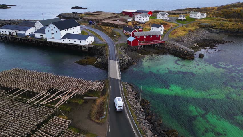 As winter's dusk descends, a scenic highway stretches past vibrant houses, their reflections shimmering in the clear waters reminiscent of Lofoten, Reine, Norway.