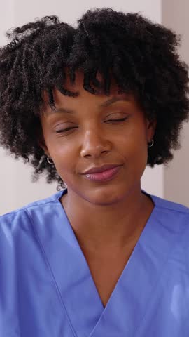 POV of young African American healthcare worker having a video call from home. Smiling young female nurse with blue scrubs talking with patient through web virtual conference. Telemedicine concept.