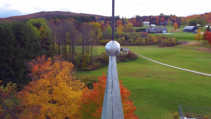 Autumn view of colorful foliage, church steeple, and rolling hills in Estrie, Québec, Canada