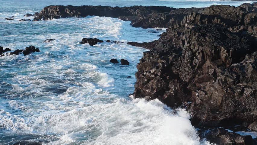 Huge waves crash on the shore, Rocky ocean coast in Iceland, Basalt cliff, Awesome power of waves breaking over dangerous rocks