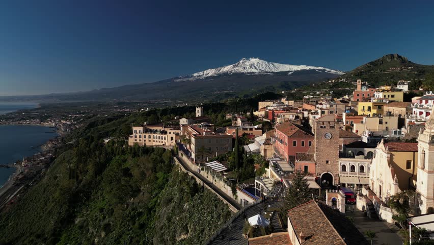 Aerial drone footage of Taormina, Sicily, showcasing the picturesque town, the Mediterranean Sea, and the majestic Mount Etna. Perfect for travel, tourism, and nature-themed projects.
