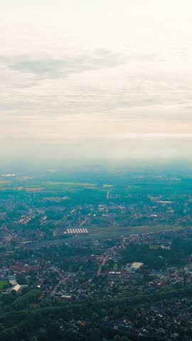 Vertical video. Ghent, Belgium. Sun rays and beautiful clouds. On the ground, a suburb of the city of Ghent with an industrial area and a railway, small houses. Ringvaart in Ghent - water channel, Ae