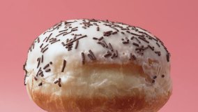 A donut with sprinkles on top. The sprinkles are brown and white. The donut rotates on a pink background. - Powered by Shutterstock - Get 15% off with code: PIKWIZARD15