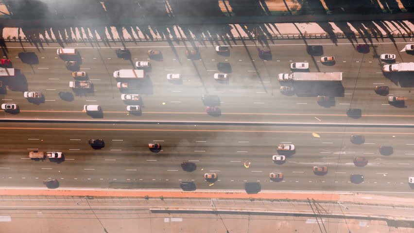 Smoke billows over the Los Angeles highway. A large fire is spreading across Los Angeles. People are leaving the areas engulfed by fire. Traffic jam of cars, evacuation.