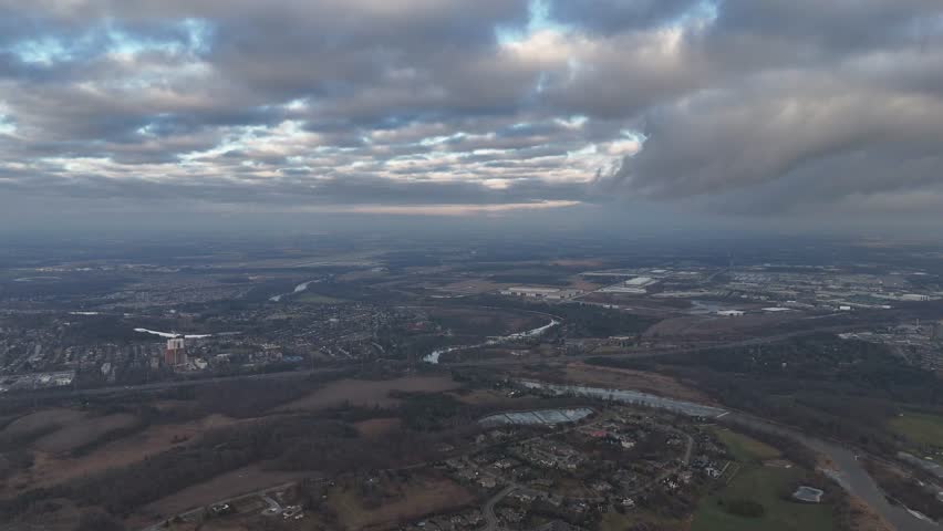 An aerial footage of dramatic cloudy sky above Kitchener, Ontario cityscape with green spaces in Canada