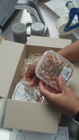 African American Shipping and Receiving Clerk Packing Cardboard Parcel with Online Orders, Food, Putting Sticker, Preparing Package for Shipping. Delivery Service of E-Commerce Store. Vertical Shot.