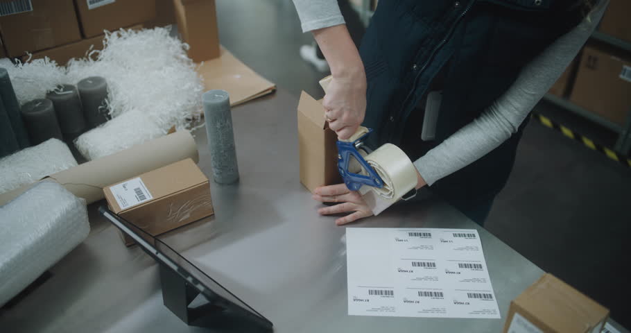 Warehouse Clerk Packs Cardboard Box with Online Order, Scans Code, Uses Tablet Computer, Prepares Parcels for Shipping to Clients. Sorting Center of E-Commerce Store, Postal Delivery Service. Close Up