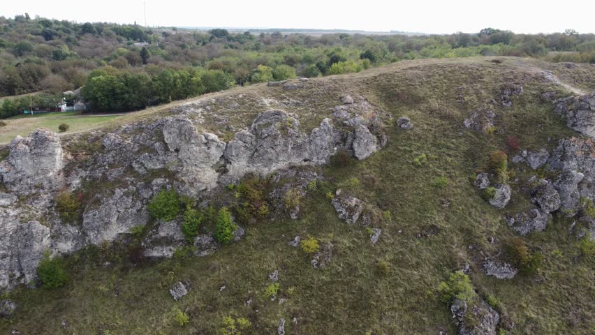 Limestone rock outcrops on steep bank of river, leaking in canyon-like valley, aerial view when moving sideways
