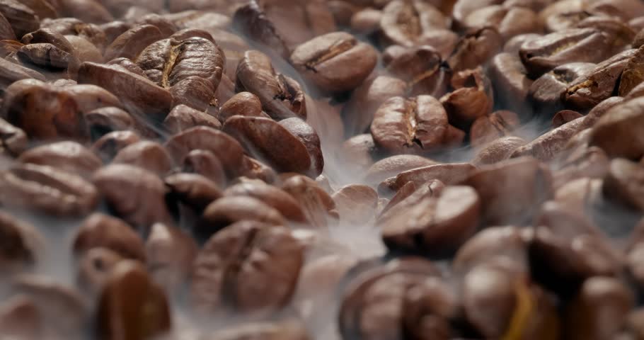 Close up of seeds of coffee. Fragrant coffee beans are roasted smoke comes from coffee beans.