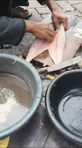The greengrocer is filling up mackerel fish and cleaning up the dirt ordered by loyal customers at his place of residence