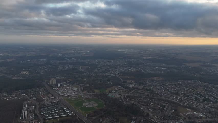An aerial view of dramatic cloudy sky above the urban Kitchener, Ontario cityscape in Canada, creating calm atmosphere over the city at sunset time
