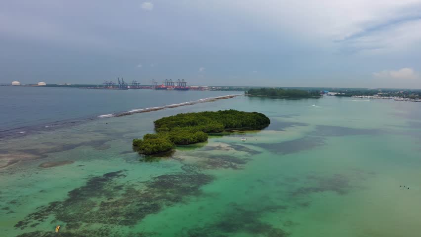 La Matica islet, impenetrable mangrove forest, Playa Boca Chica beach, Caucedo port in background, Santo Domingo in Dominican Republic. Aerial drone orbiting, sky for copy space