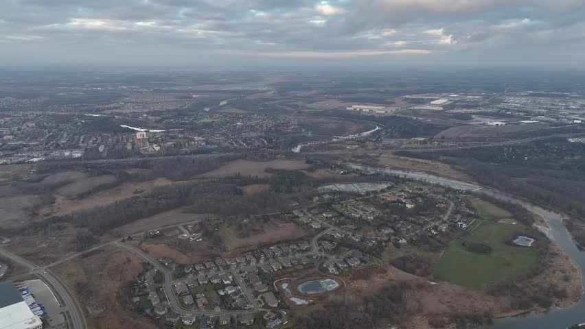 A drone footage of dramatic cloudy sky above the urban Kitchener, Ontario cityscape with river and green spaces in Canada