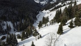 A drone shot of a resort with houses on snowy mountain peak in winter, a landscape of pine trees covered with snow - Powered by Shutterstock - Get 15% off with code: PIKWIZARD15