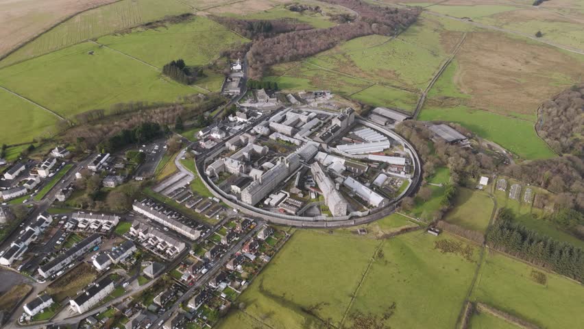 Aerial view of Princetown set amid sweeping Dartmoor landscapes with scattered buildings, rolling hills, and open fields capturing quiet rural character