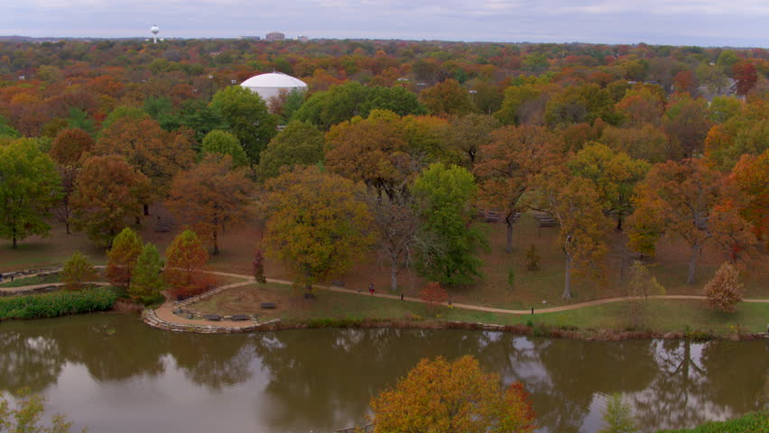 Aerial landscape of beautiful trees at peak color and a pond in a park in Kirkwood neighborhood of St. Louis, Missouri on a beautiful cloudy day in Autumn.
