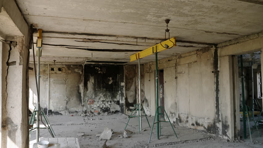 Burnt interior of Mariupol apartment shows war impact. Charred residence with cracked walls, debris fill abandoned flat. Destroyed building interior for war documentary or news story. Slow motion.