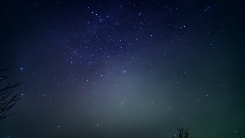 Hazy northern lights appear with green glow dancing in the night sky over Finland as stars and milky way rotate above