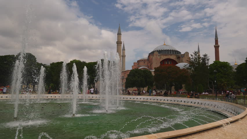 Fountains in front of Hagia Sophia, showcasing intricate water displays against a historic backdrop. The stunning architecture and lush greenery create an inviting atmosphere in Istanbul. Daytime